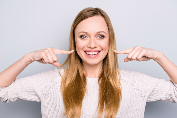 smiling woman pointing to her face